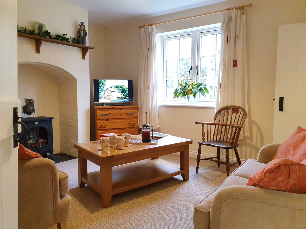 Cozy holiday cottage living room with fireplace, wooden furniture, sunny window, and comfortable seating