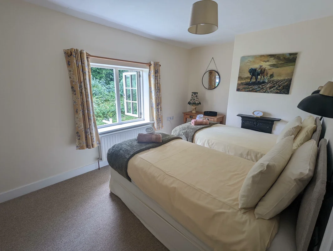 Cozy twin bedroom with garden view, two beds, soft cushions, and warm decor